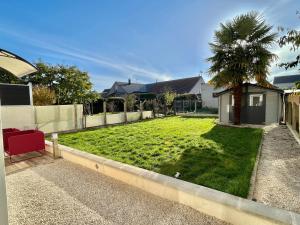 a backyard with a grass yard with a palm tree at Studio avec cuisine, salle de bain et garage privé proximité 24h in Le Mans