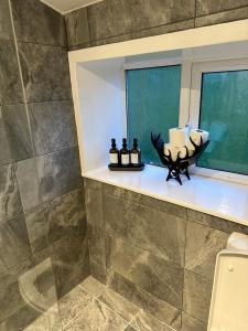 a bathroom with a window and some candles on a shelf at Ladybird Cottage in Barrowford