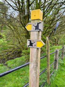 a wooden sign with birds on it next to a fence at Ladybird Cottage in Barrowford