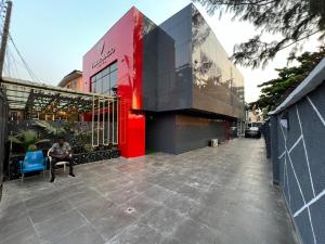 伊凯贾Villa Palazzo Hotel 2的坐在建筑物前椅子上的男人