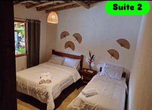 een slaapkamer met twee bedden met parasols aan de muur bij Rancho Bela Vista Sapirara in Trancoso
