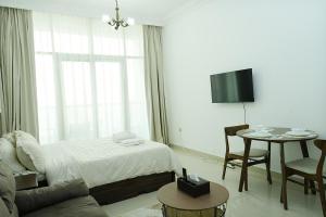 a bedroom with a bed and a table and a tv at Cozy Private Studio -Near Beach -City View -Downtown Sharjah - Pool & Gym in Sharjah