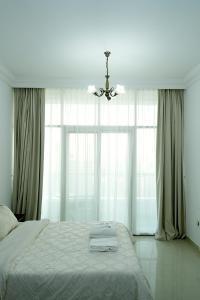 a bedroom with a bed with a chandelier and large windows at Cozy Private Studio -Near Beach -City View -Downtown Sharjah - Pool & Gym in Sharjah