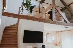 a living room with a staircase and a flat screen tv at The Burgundy - Boutique B&B in Bruges