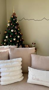 a christmas tree in the corner of a room with a couch at La Villa face au Lac in Saramon