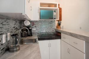 a kitchen with a sink and a microwave at Pool, Near Marinas, Reefs, Family Fun, 2BR Condo, Main Level in Cozumel