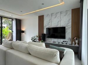 a living room with a white couch and a flat screen tv at Stay Tuned Pool Villa in Pattaya in Ban Huai Yai