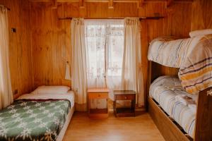 a bedroom with two bunk beds and a window at La Lomita Guadal in Puerto Guadal