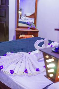 a white bed with purple flowers on top of it at Riyon Rooms and Restaurant in Weligama