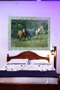 a bedroom with a painting of horses running in a field at Riyon Rooms and Restaurant in Weligama