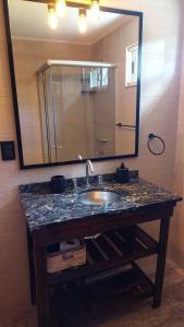 a bathroom with a sink and a large mirror at Cabañas Altos del Bosque in Mar del Plata