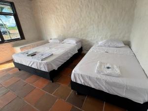 two twin beds in a room with a window at HOTEL PARQUE TEMÁTICO VIDESGk in Saravena