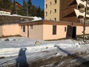 una sombra de una persona parada en la nieve frente a un edificio en Casa vacanze Monginevro, en Montgenèvre