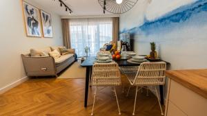 a living room with a table and chairs and a couch at Apartament ODNOWA M29 basen i jacuzzi in Dziwnów
