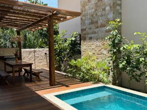 an outdoor swimming pool with a table and a pergola at Bahia Soul - Vilas de Maré - Taipu de Fora - Península de Maraú in Marau