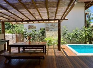 a wooden patio with a table and a swimming pool at Bahia Soul - Vilas de Maré - Taipu de Fora - Península de Maraú in Marau