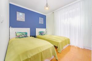 two beds in a room with blue walls at Madeira Dreams in Caniço