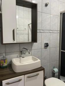 a bathroom with a sink and a mirror and a toilet at Casa Gil in Foz do Iguaçu