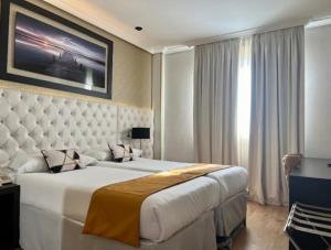 a bedroom with a large white bed with a large window at Hotel Suites Feria de Madrid in Madrid