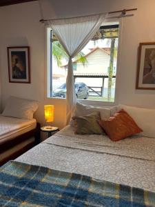 a bedroom with two beds and a window with a car outside at Casinhas do Peró Refúgio com Jardim e WiFi Rápido in Cabo Frio