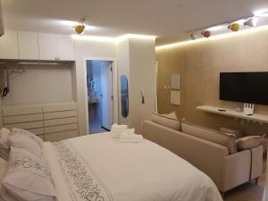 a bedroom with a bed and a couch and a flat screen tv at Apart-hotel Theotókos Flats in Piumhi