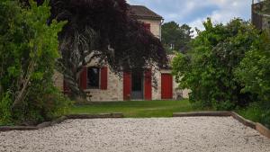 a house with red doors and a yard with trees at Château Batsères in Landiras