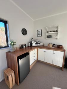 アレクサンドラにあるCariad Apartmentの白いキャビネットと木製カウンター付きのキッチン