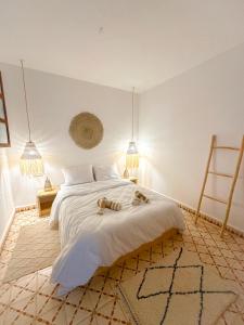a bedroom with a large white bed with two animals on it at Eco Bay Surf House in Agadir
