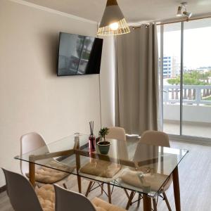 a dining room with a glass table and chairs at Acogedor departamento cerca de avenida del Mar in La Serena