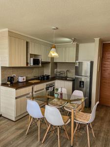 a kitchen with a glass table and white chairs at Acogedor departamento cerca de avenida del Mar in La Serena