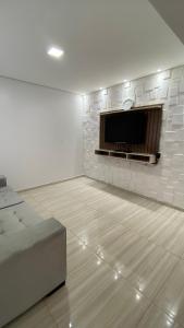 a living room with a tv and a brick wall at Sobrado Vila Industrial in Toledo