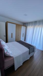 a bedroom with a white bed and a couch at Sobrado Vila Industrial in Toledo