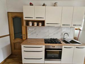 una cucina con mobili bianchi e un forno a piano cottura di Apartma Cipresa a Rogatec