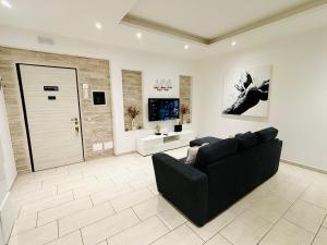 a living room with a black couch and a tv at Espero Ostia in Lido di Ostia