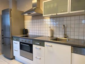 eine Küche mit weißen Schränken und einem Edelstahlkühlschrank in der Unterkunft CityBude in Gerolstein