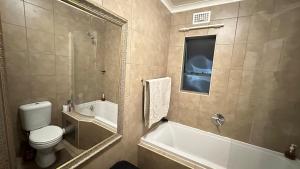 a bathroom with a toilet and a tub and a sink at Nyasa Apartment in Johannesburg