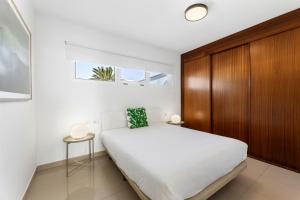 Schlafzimmer mit einem weißen Bett und einem Holzschrank in der Unterkunft La casa de la playa in Playa Honda