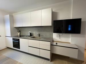 a kitchen with white cabinets and a sink and a tv at Ciasa Enrico in Arabba