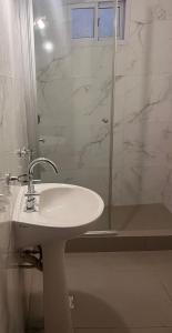 Un baño blanco con lavabo y ducha. en Estrella de mar, en Necochea