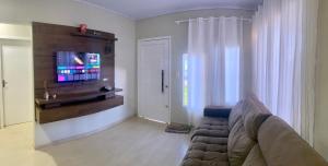 a living room with a couch and a flat screen tv at Casa térrea para família no centro de Ametista! in Ametista do Sul