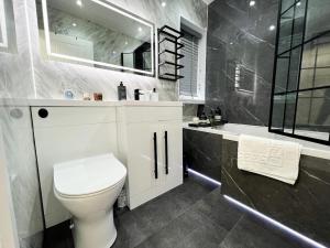 a bathroom with a toilet and a sink and a tub at Spectacular Modern Glasgow Home Luxury King Bed in Glasgow +10 photos