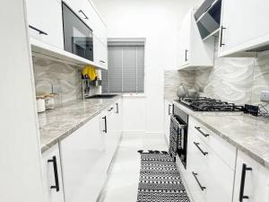 a white kitchen with white cabinets and a stove at Spectacular Modern Glasgow Home Luxury King Bed in Glasgow