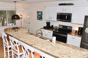 - une cuisine avec des placards blancs et un plan de travail en granit dans l'établissement Golf/ Beach Penthouse Condo, à Sunset Beach
