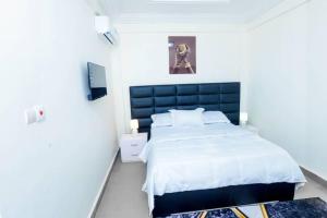 a bedroom with a large bed with a blue headboard at Résidence Le Prestige in Yaoundé