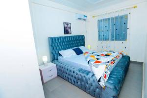 a bedroom with a blue bed with a blue headboard at Résidence Le Prestige in Yaoundé +3 photos