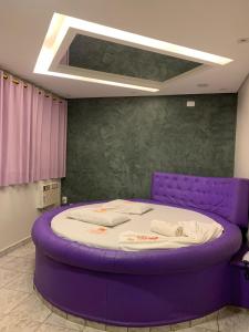 a large purple bed in a room with a ceiling at Caribe Palace Hotel Samambaia Sul in Brasilia