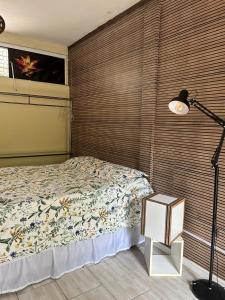 a bedroom with a bed next to a wooden wall at Studio Dunas Porto Lagoa in Florianópolis