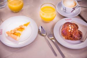 a table with two plates of food and two glasses of orange juice at Hotel Ristorante Continental in Osio Sotto