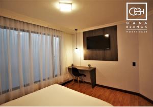 a hotel room with a desk and a television at Casa Blanca Hospedaje Pasto SAS in Pasto