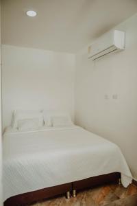 a white bed in a room with a white wall at Comfort in Valledupar